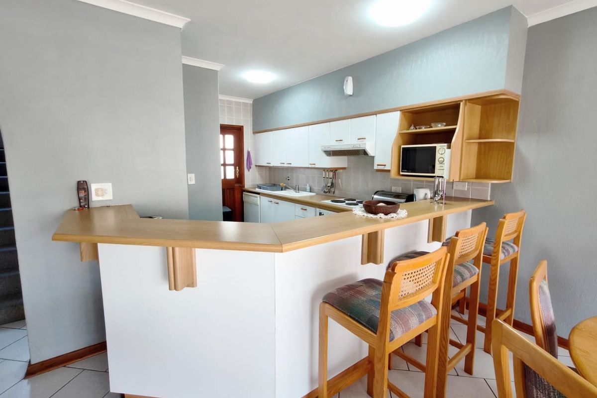 Functional kitchen featuring a breakfast bar, laminate countertops, built-in cabinetry, and tiled flooring, offering a practical layout for daily use.