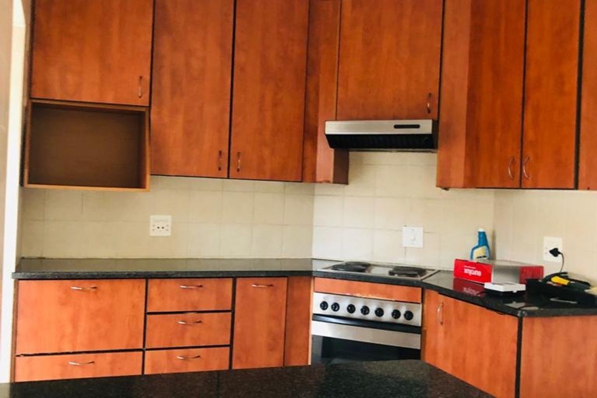 A functional kitchen featuring wooden cabinetry, granite countertops, and built-in cooking appliances including an oven and hob.