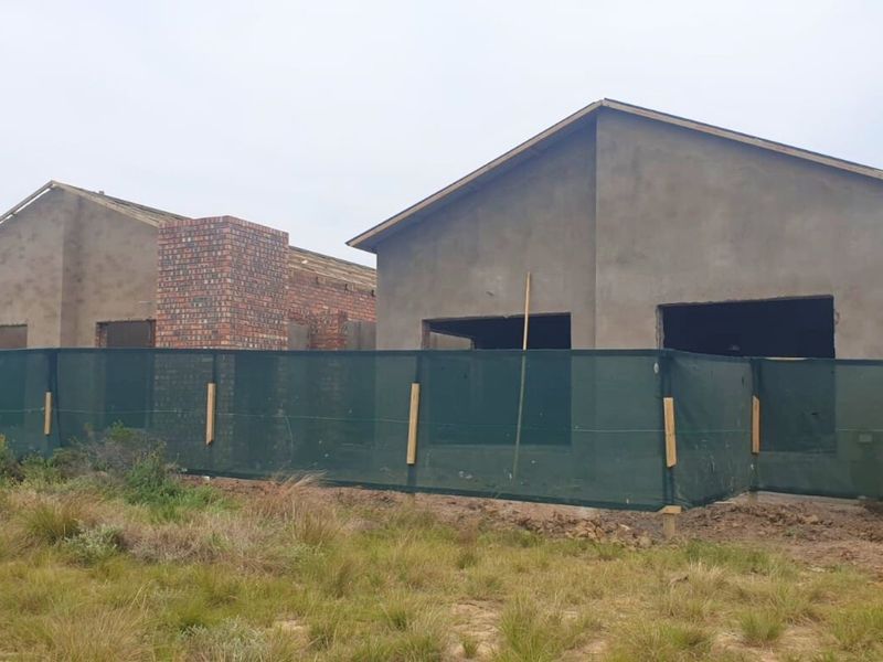 Rear view of townhouse units currently under construction, featuring exposed brick chimneys and unfinished plastered exterior walls.