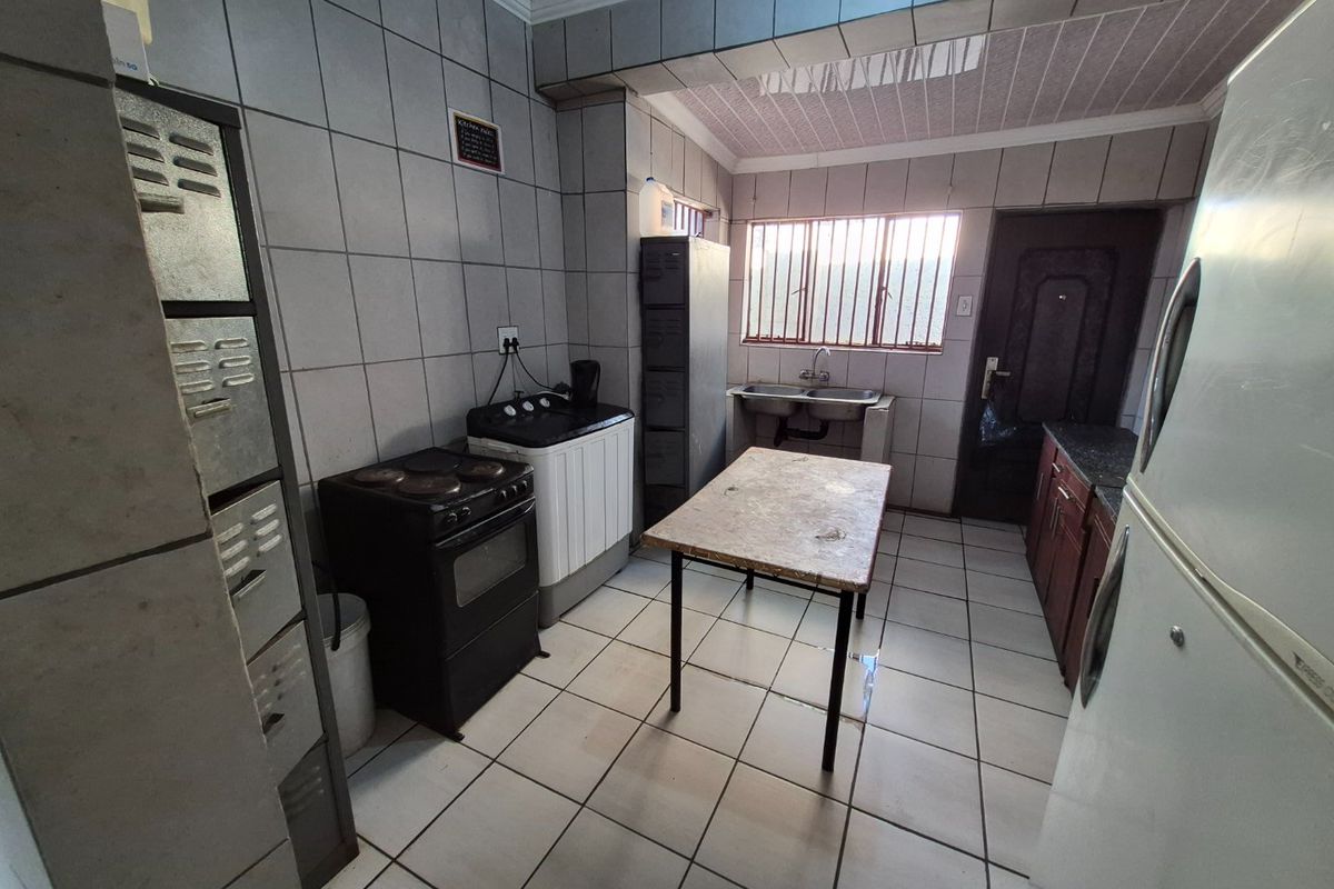 A functional kitchen space featuring tiled walls and floors, a double basin sink, and built-in cabinetry, offering potential for modernization and layout optimization.