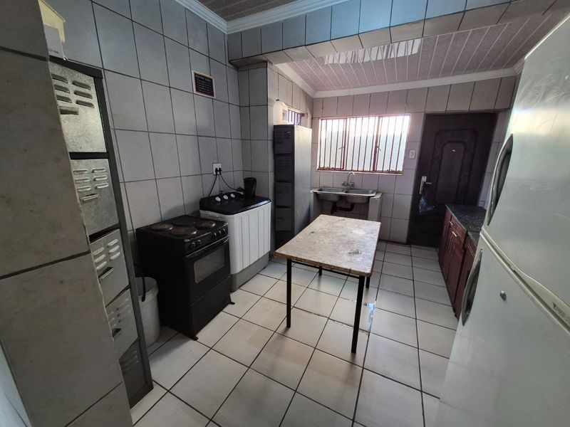 A functional kitchen space featuring tiled walls and floors, a double basin sink, and built-in cabinetry, offering potential for modernization and layout optimization.