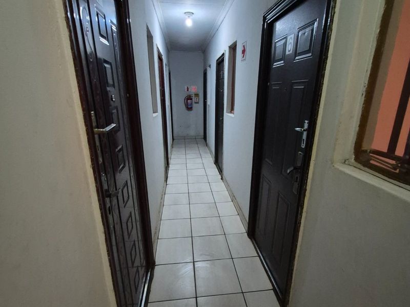 A functional interior hallway featuring tiled flooring, multiple security doors, and wall-mounted fire safety equipment.