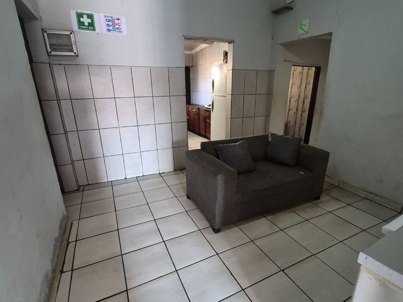 A living area featuring tiled flooring and wall cladding with visible signs of wear and wall cracks requiring maintenance.