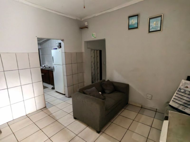 Open plan living area featuring tiled flooring and partial wall tiling, providing a functional space with direct access to the adjacent kitchen area.