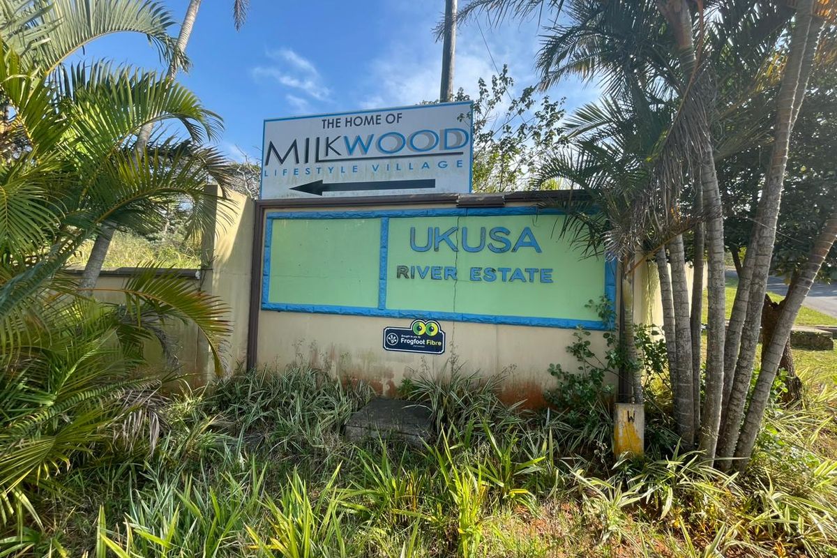 Entrance signage for Ukusa River Estate and Milkwood Lifestyle Village, featuring a boundary wall and surrounding landscaped garden area.