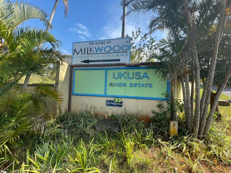 Entrance signage for Ukusa River Estate and Milkwood Lifestyle Village, featuring a boundary wall and surrounding landscaped garden area.