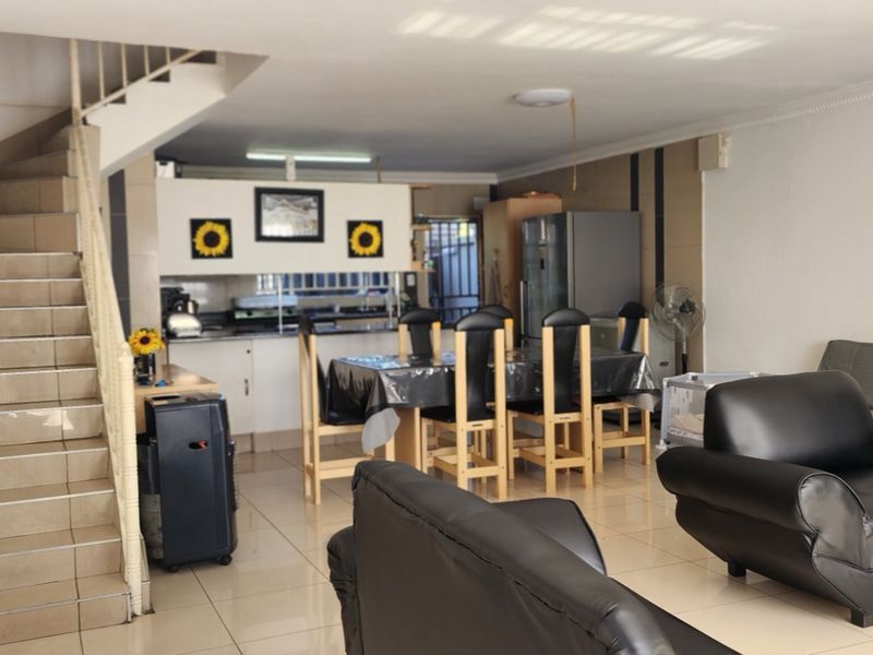 Open plan living and dining area featuring tiled flooring and a staircase leading to the upper level.