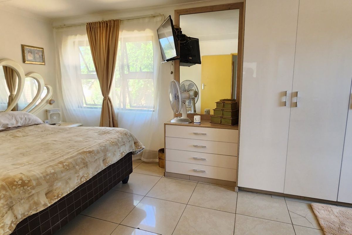 A bedroom featuring tiled flooring, a large built-in wardrobe, and a built-in vanity mirror with storage drawers.