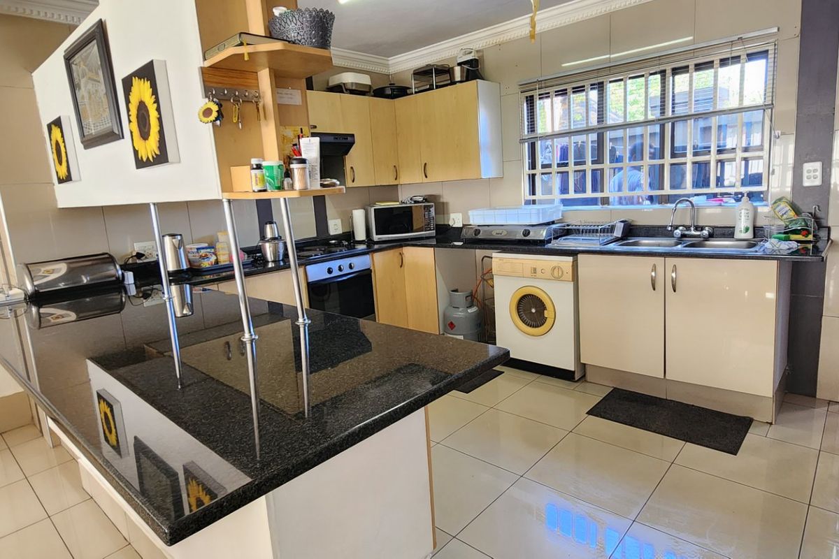 A functional kitchen featuring granite countertops, built-in cabinetry, an integrated oven and hob, and tiled flooring with a window overlooking the exterior.