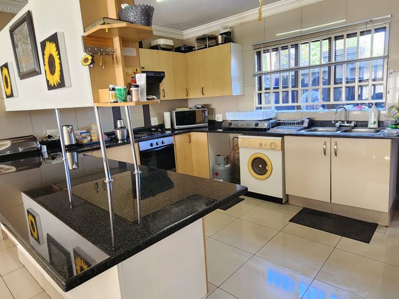 A functional kitchen featuring granite countertops, built-in cabinetry, an integrated oven and hob, and tiled flooring with a window overlooking the exterior.