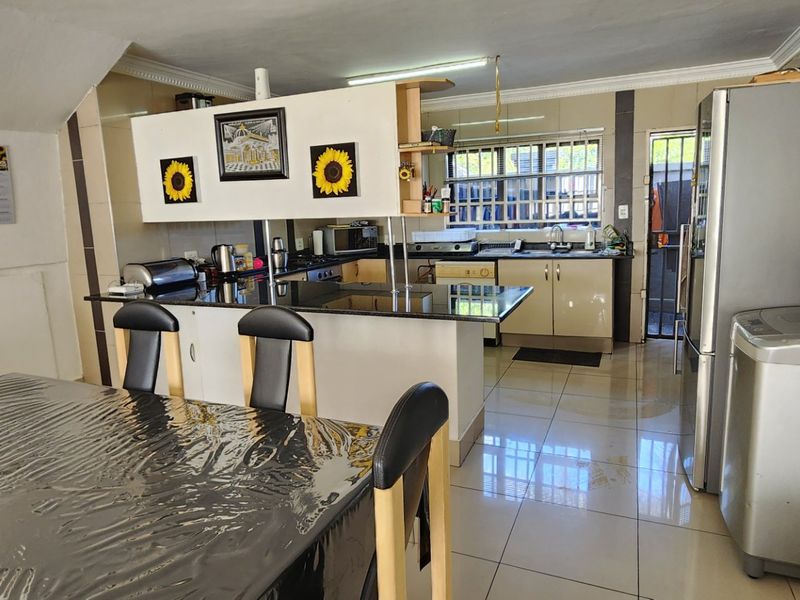 Open-plan kitchen and dining area featuring granite countertops, tiled flooring, and built-in cabinetry, providing a functional layout for daily living.