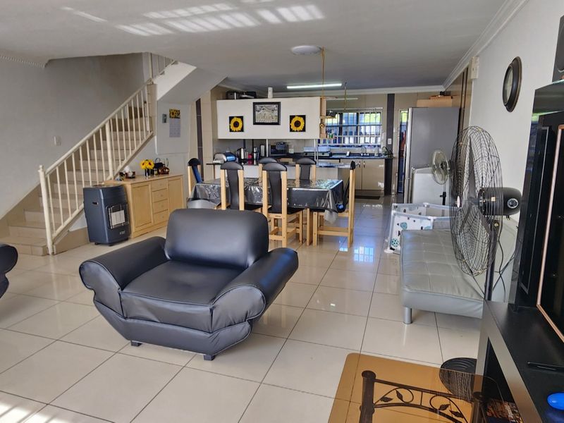 Open plan living and dining area featuring tiled flooring and a staircase, flowing into a functional kitchen space.