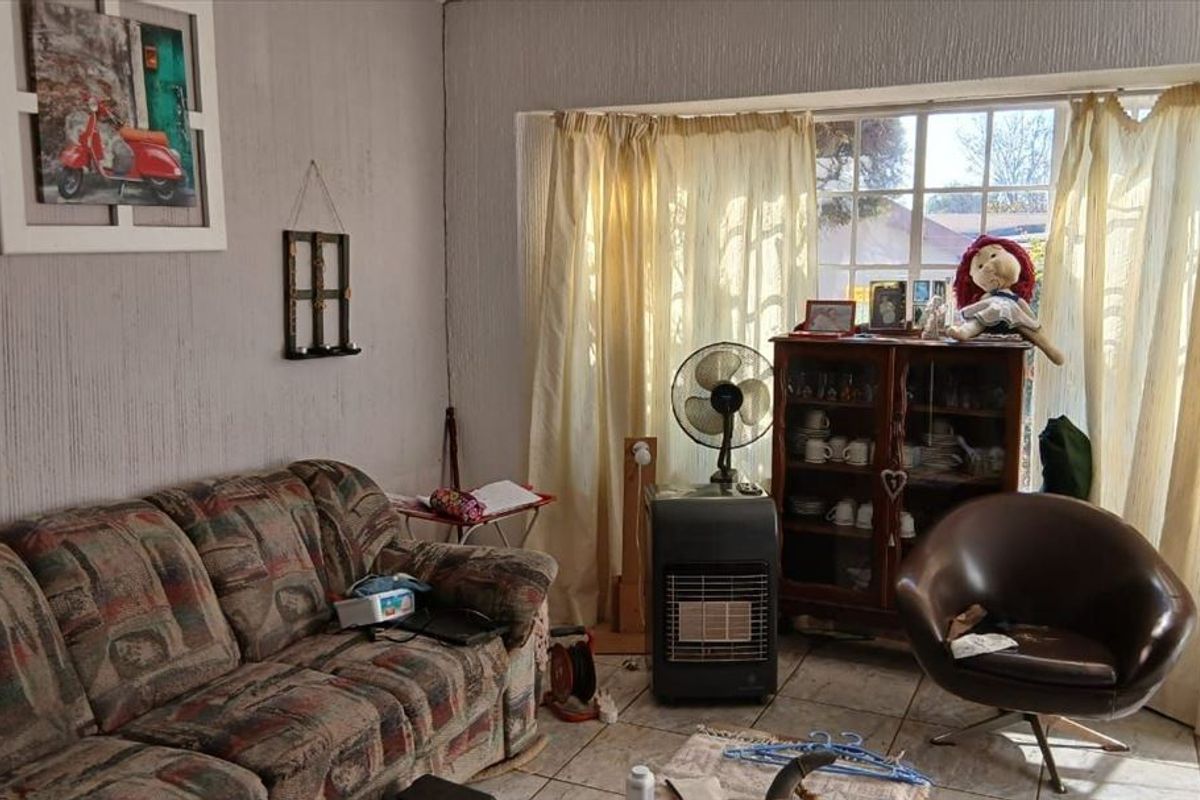 A living room featuring tiled flooring, textured walls, and a large window that allows for natural light.