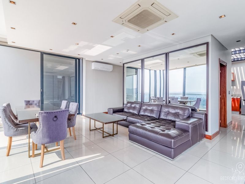 Spacious open-plan living and dining area featuring polished tiled floors, recessed lighting, ducted air conditioning, and large glass doors leading to an outdoor space.