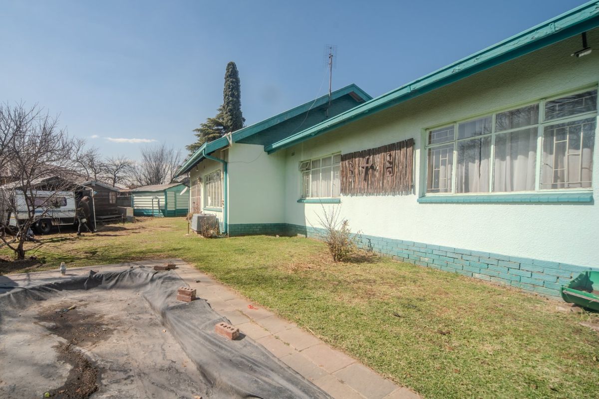 Rear view of the house featuring a pool area with a lawn and exterior brick and plaster finishes.