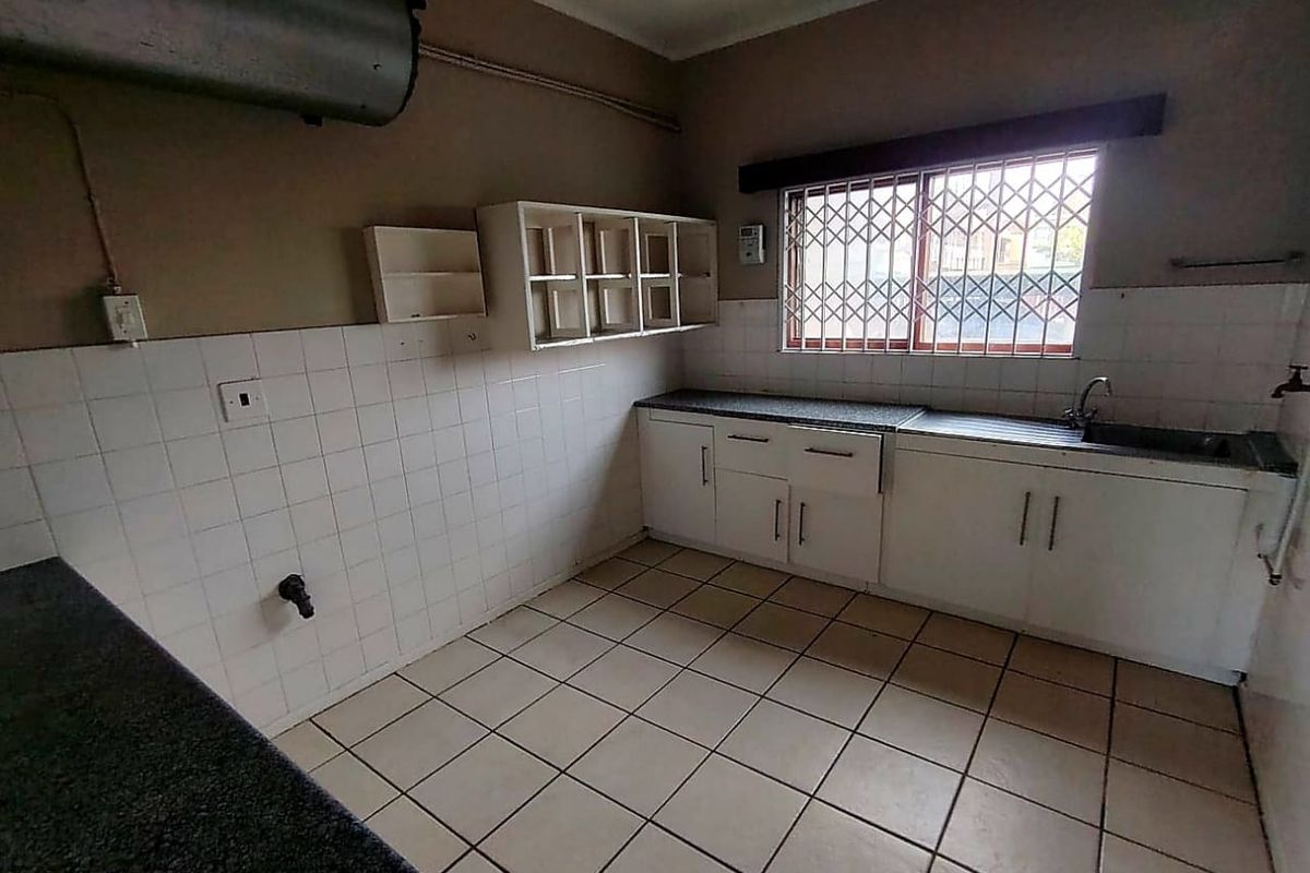 A functional kitchen space featuring built-in cabinetry, tiled splashbacks, and a stainless steel sink, offering a blank canvas for modern renovation.