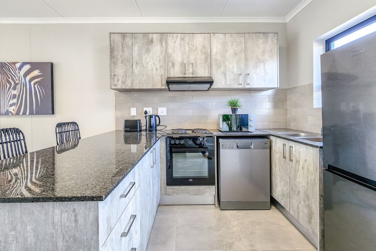Modern kitchen featuring granite countertops, built-in cabinetry, integrated oven and hob, and a tiled backsplash in a clean, functional layout.