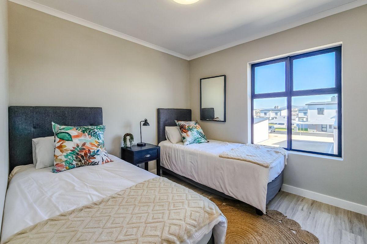 A well-maintained bedroom featuring neutral wall tones, laminate flooring, and a large window providing natural light and neighbourhood views.