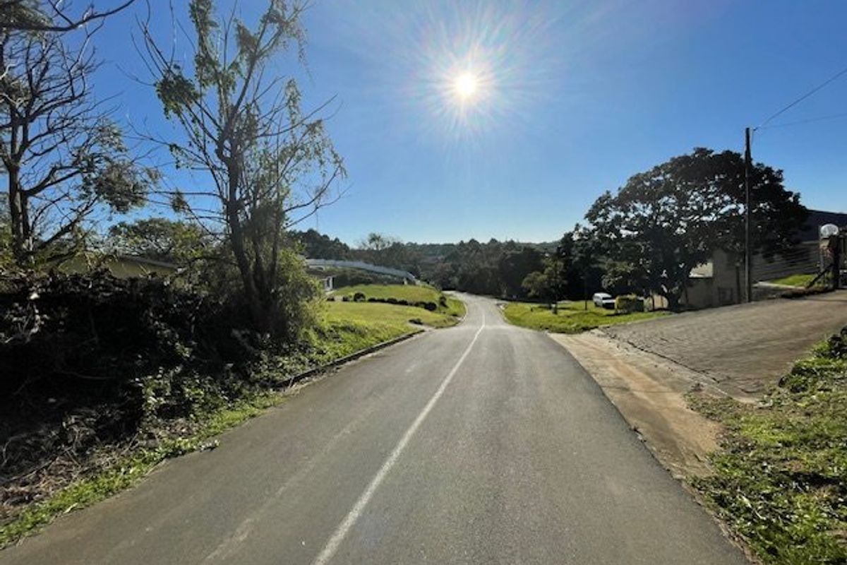 A view of the paved street leading towards the residential property, showcasing the surrounding landscape and neighborhood approach.