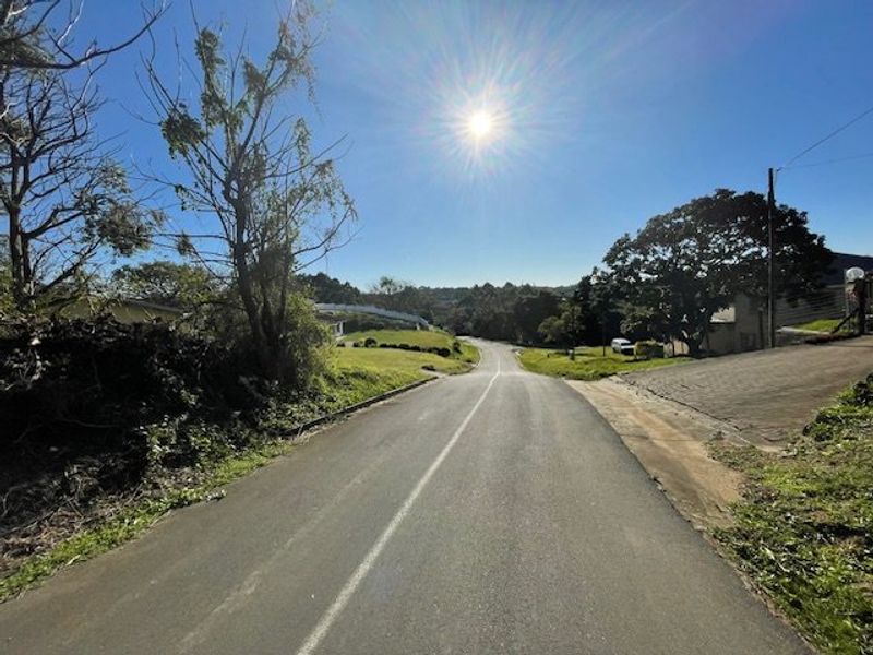 A view of the paved street leading towards the residential property, showcasing the surrounding landscape and neighborhood approach.