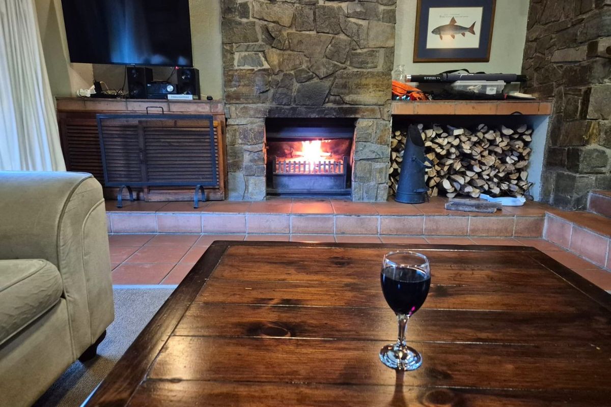 Cozy living room featuring a prominent stone fireplace with a built-in firewood storage nook and a tiled hearth.