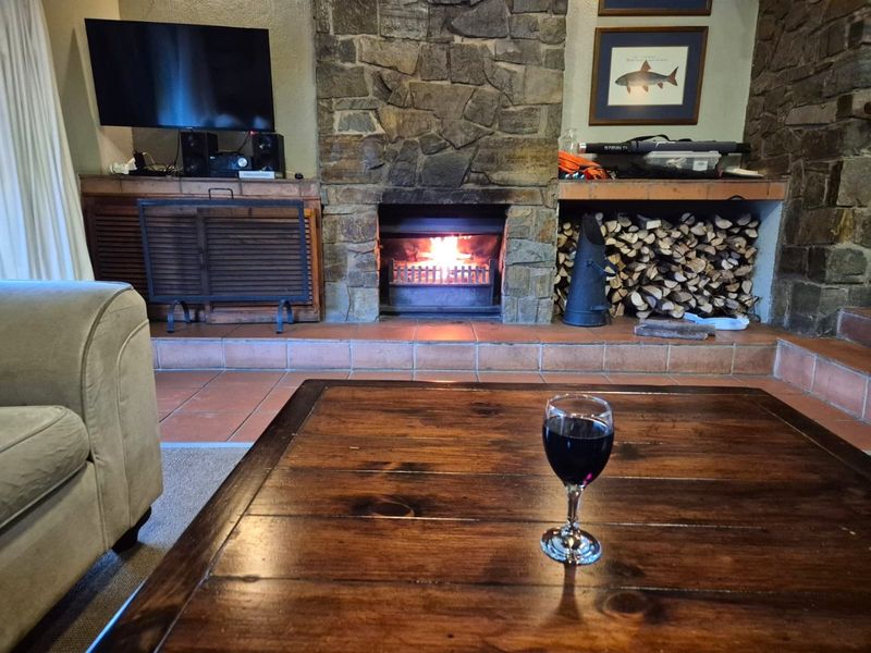 Cozy living room featuring a prominent stone fireplace with a built-in firewood storage nook and a tiled hearth.
