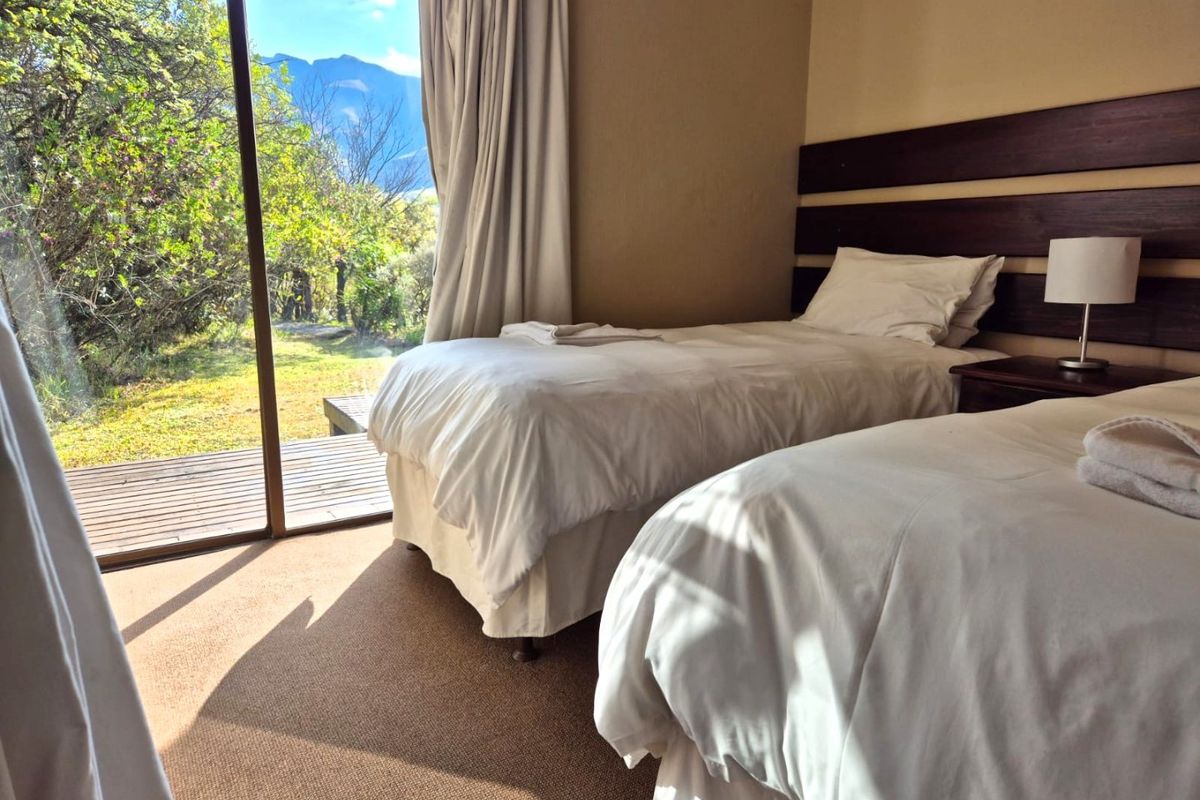 A bedroom featuring carpeted flooring and a large sliding glass door providing access to an outdoor deck with scenic mountain views.
