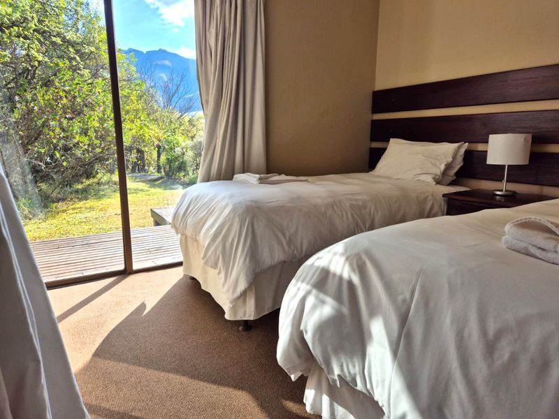 A bedroom featuring carpeted flooring and a large sliding glass door providing access to an outdoor deck with scenic mountain views.