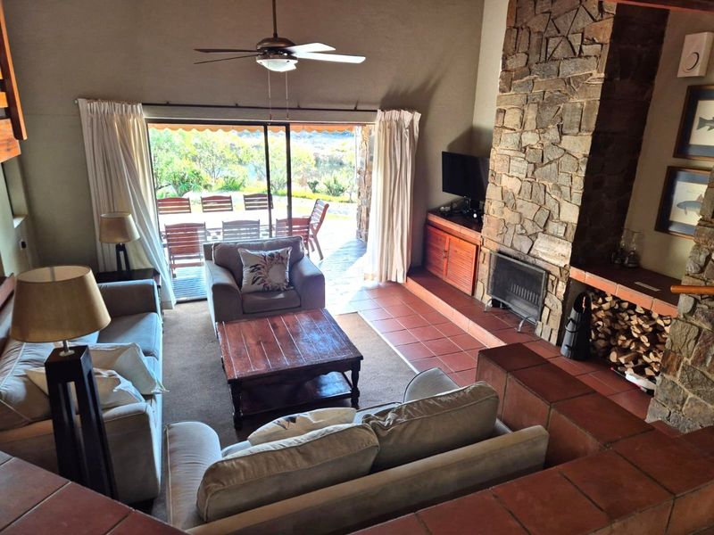 Spacious living room featuring a prominent stone fireplace, tiled flooring, and large sliding glass doors providing access to an outdoor patio area.