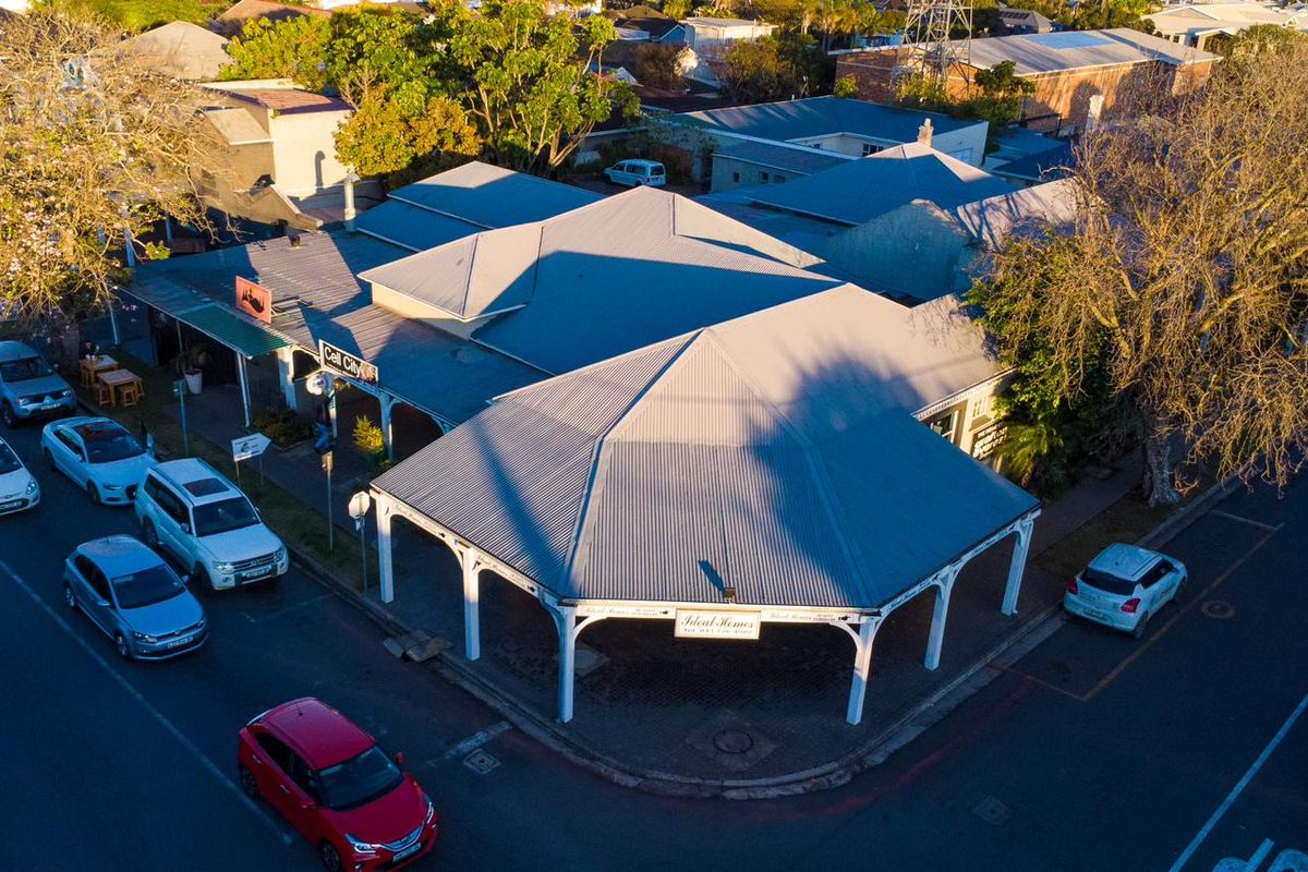Aerial view of a commercial property featuring a prominent corner position with a covered veranda and corrugated metal roofing.