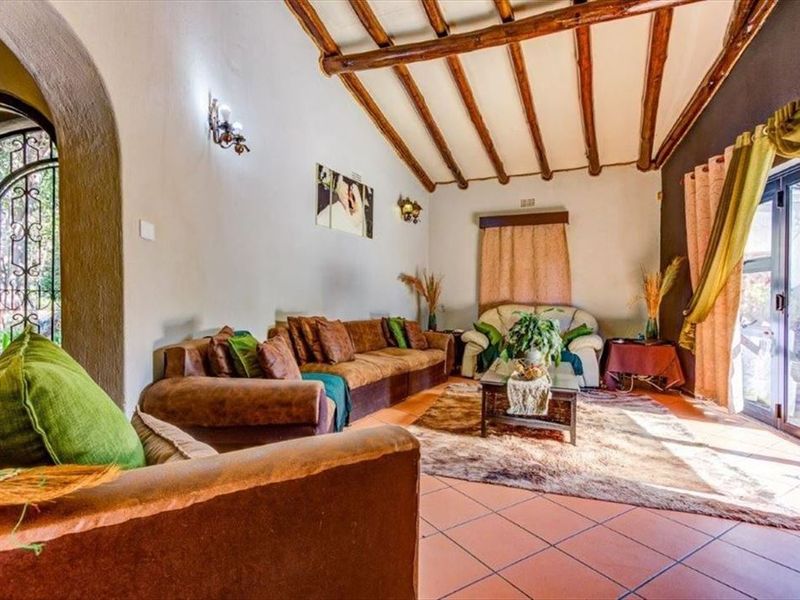 Spacious living room featuring exposed timber ceiling beams, terracotta-style tiled flooring, and large sliding glass doors providing access to the outdoor area.