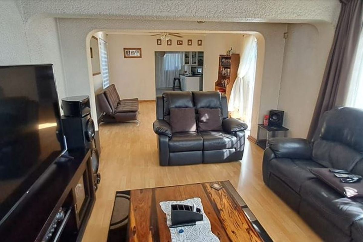 Open plan living area featuring light wood laminate flooring and a distinct arched transition leading to an adjacent room.