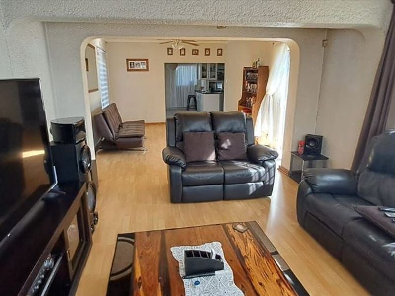 Open plan living area featuring light wood laminate flooring and a distinct arched transition leading to an adjacent room.