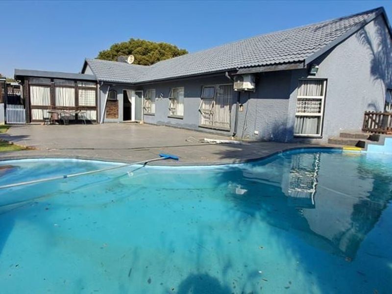 Rear view of the property featuring a swimming pool, paved patio area, and direct access to the main house structure.