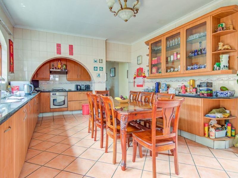 Spacious kitchen and dining area featuring wooden cabinetry, granite countertops, built-in oven, and tiled flooring.
