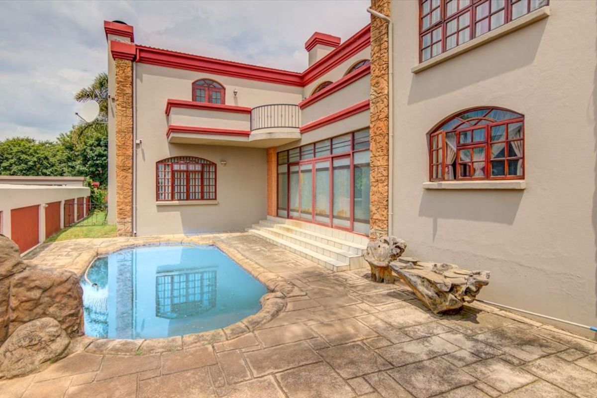 Rear exterior view featuring a swimming pool, paved patio area, and multi-story building facade with arched windows and a balcony.