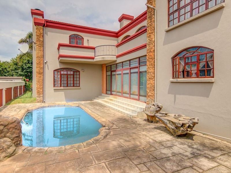 Rear exterior view featuring a swimming pool, paved patio area, and multi-story building facade with arched windows and a balcony.