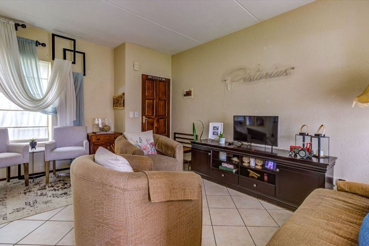 A comfortable living room featuring tiled flooring and a classic timber door, offering a functional and lived-in space.