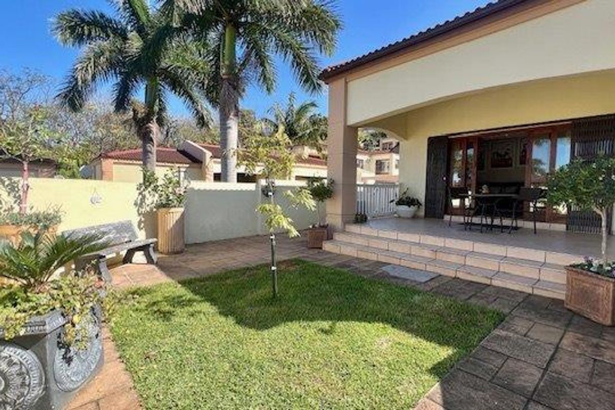 A private rear patio area featuring tiled flooring, steps leading to the garden, and sliding glass doors providing access to the interior living space.