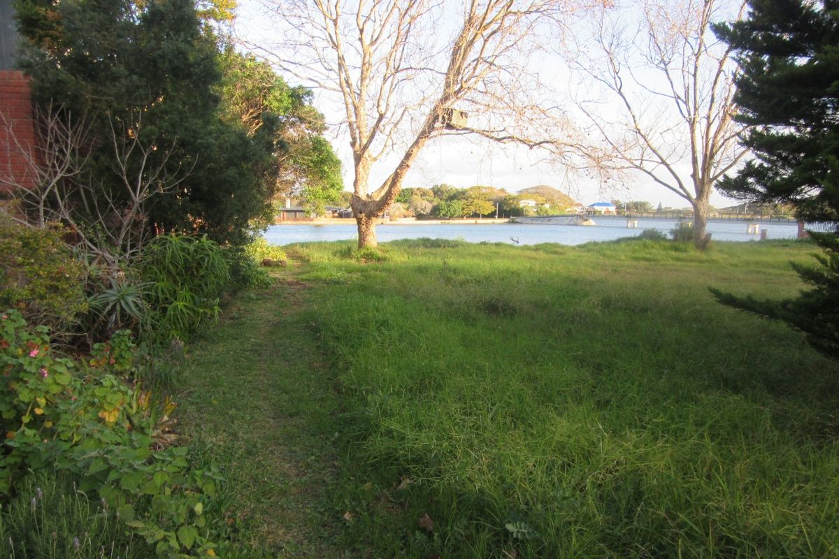 A scenic view of the waterfront from the residential property, featuring mature trees and a natural grassed landscape.