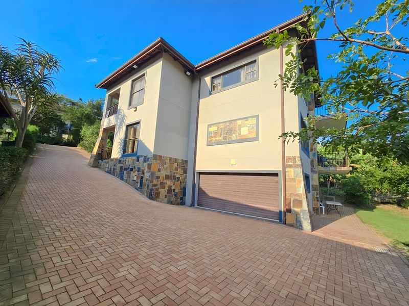 A multi-story residential property featuring a paved driveway, stone cladding accents, and an integrated garage.