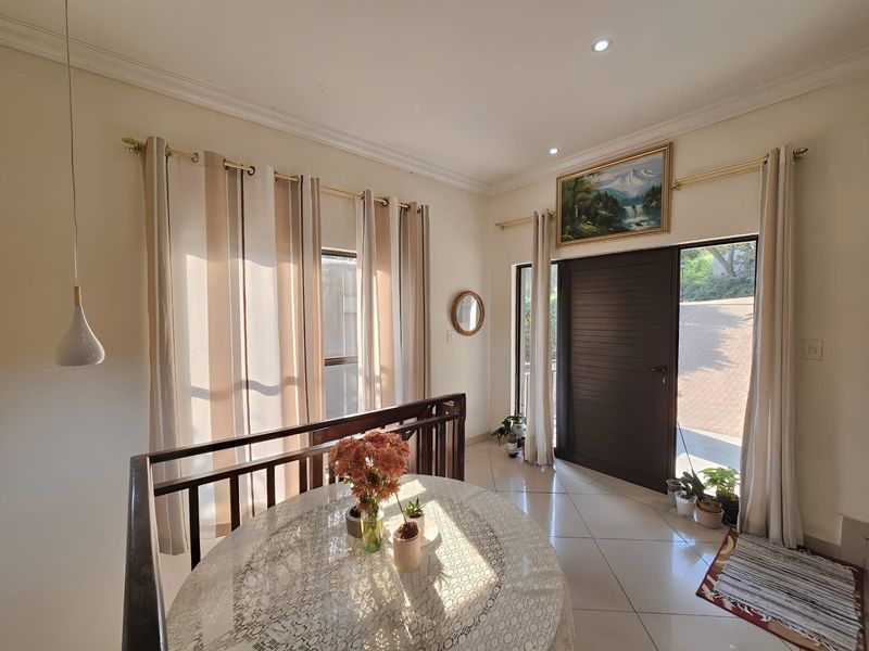 Bright and welcoming entrance hall featuring tiled flooring, recessed lighting, and a timber staircase railing, providing a clean and well-maintained transition into the home.