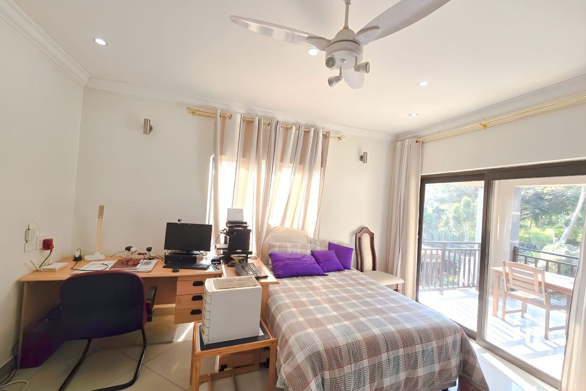 A well-lit bedroom featuring tiled flooring, a ceiling fan, and large sliding glass doors that provide access to an outdoor balcony.