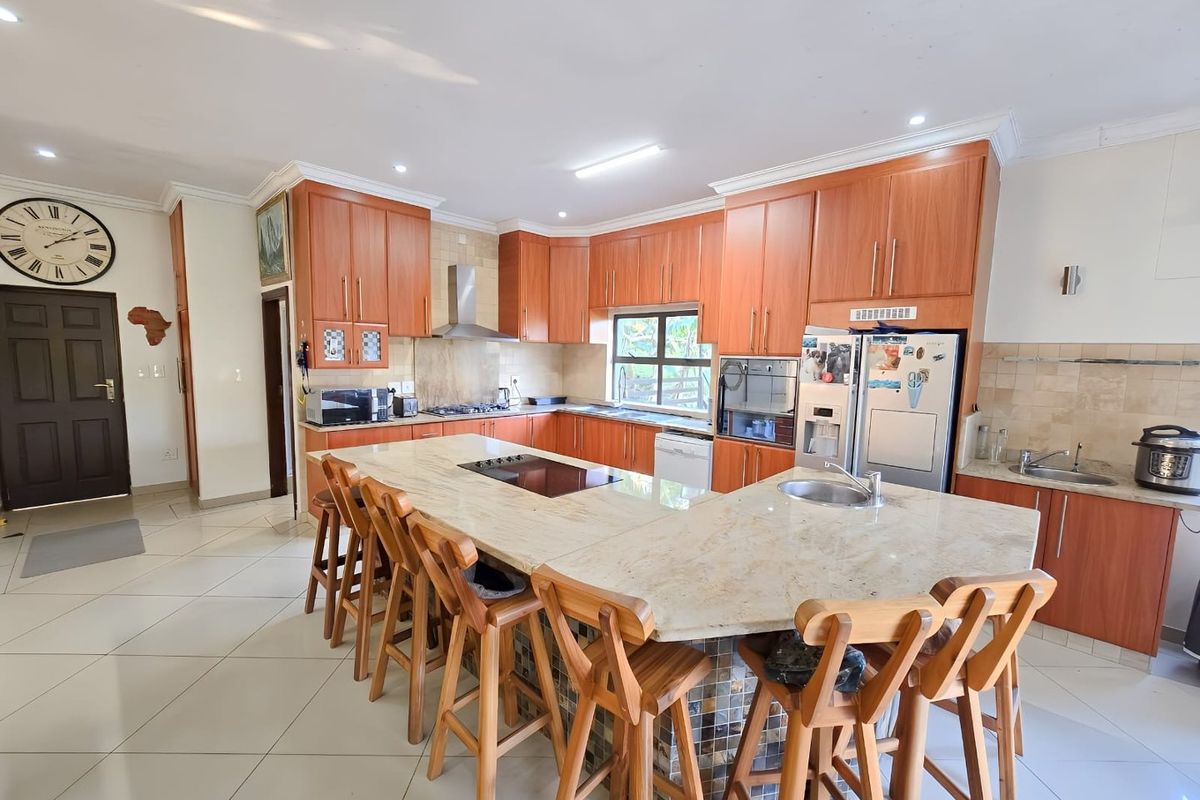 Spacious kitchen featuring extensive wooden cabinetry, granite countertops, a large central island with seating, and integrated appliances.