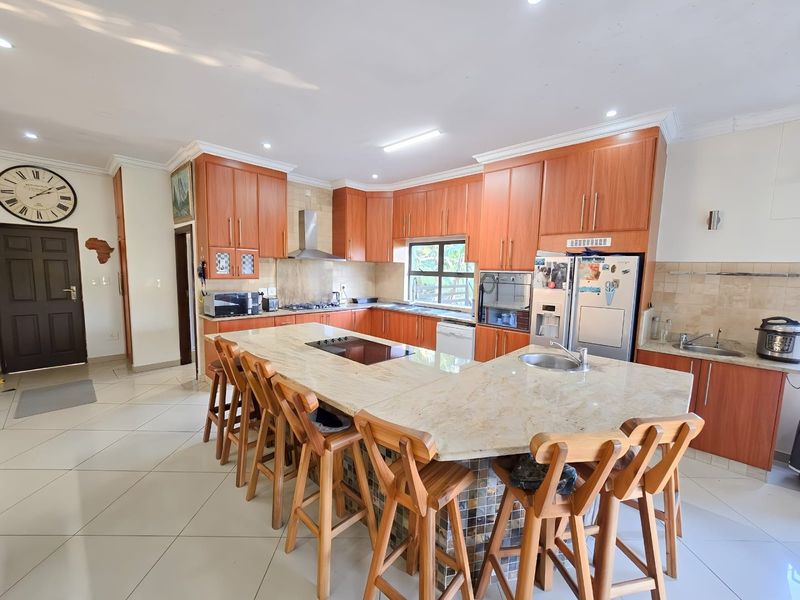 Spacious kitchen featuring extensive wooden cabinetry, granite countertops, a large central island with seating, and integrated appliances.