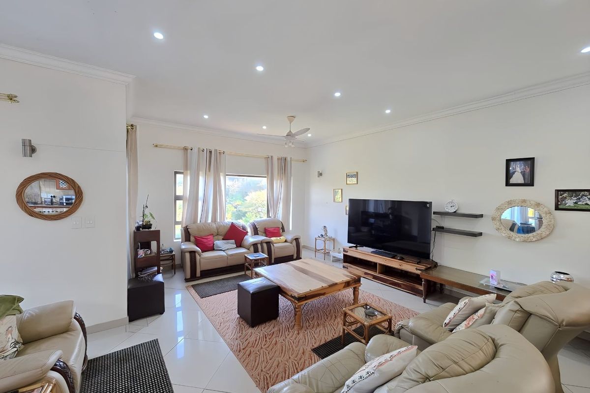 Spacious living room featuring polished tiled flooring, recessed downlighting, and a ceiling fan, creating a bright and comfortable family entertainment area.