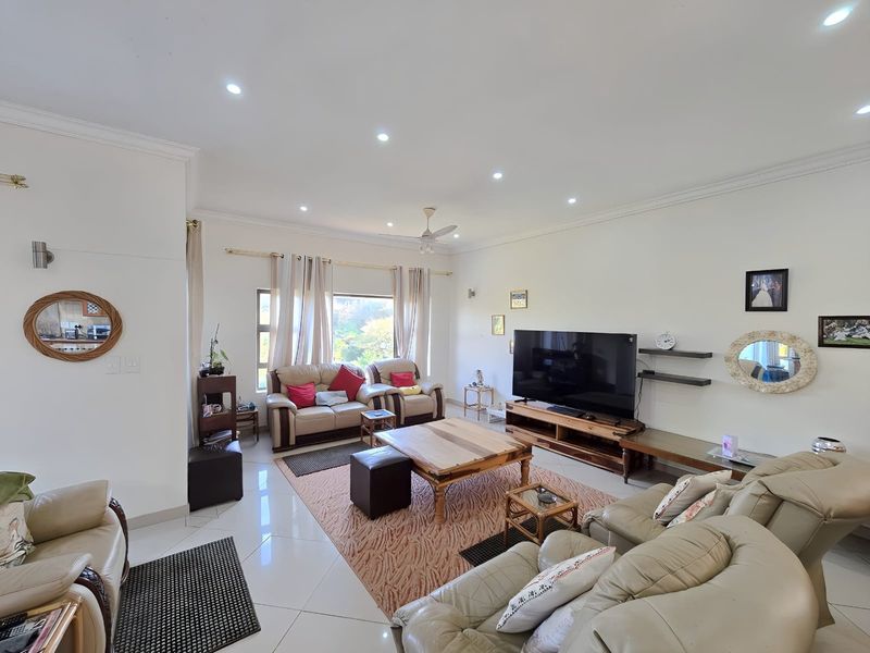 Spacious living room featuring polished tiled flooring, recessed downlighting, and a ceiling fan, creating a bright and comfortable family entertainment area.