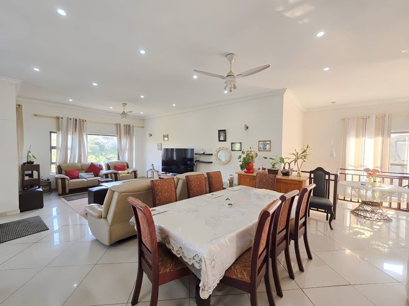 Spacious open-plan living and dining area featuring polished porcelain floor tiles, recessed downlighting, and ceiling fans throughout.