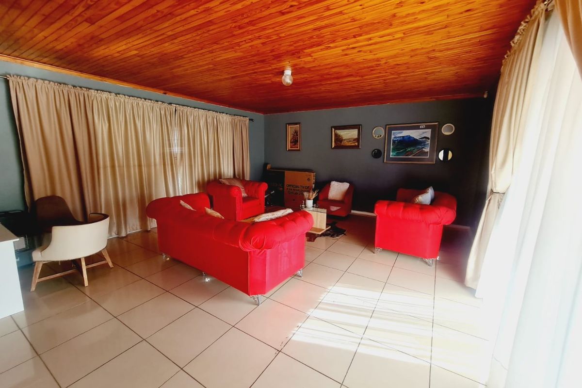 Spacious living room featuring a warm timber tongue and groove ceiling and neutral ceramic floor tiles, offering a comfortable and inviting atmosphere.