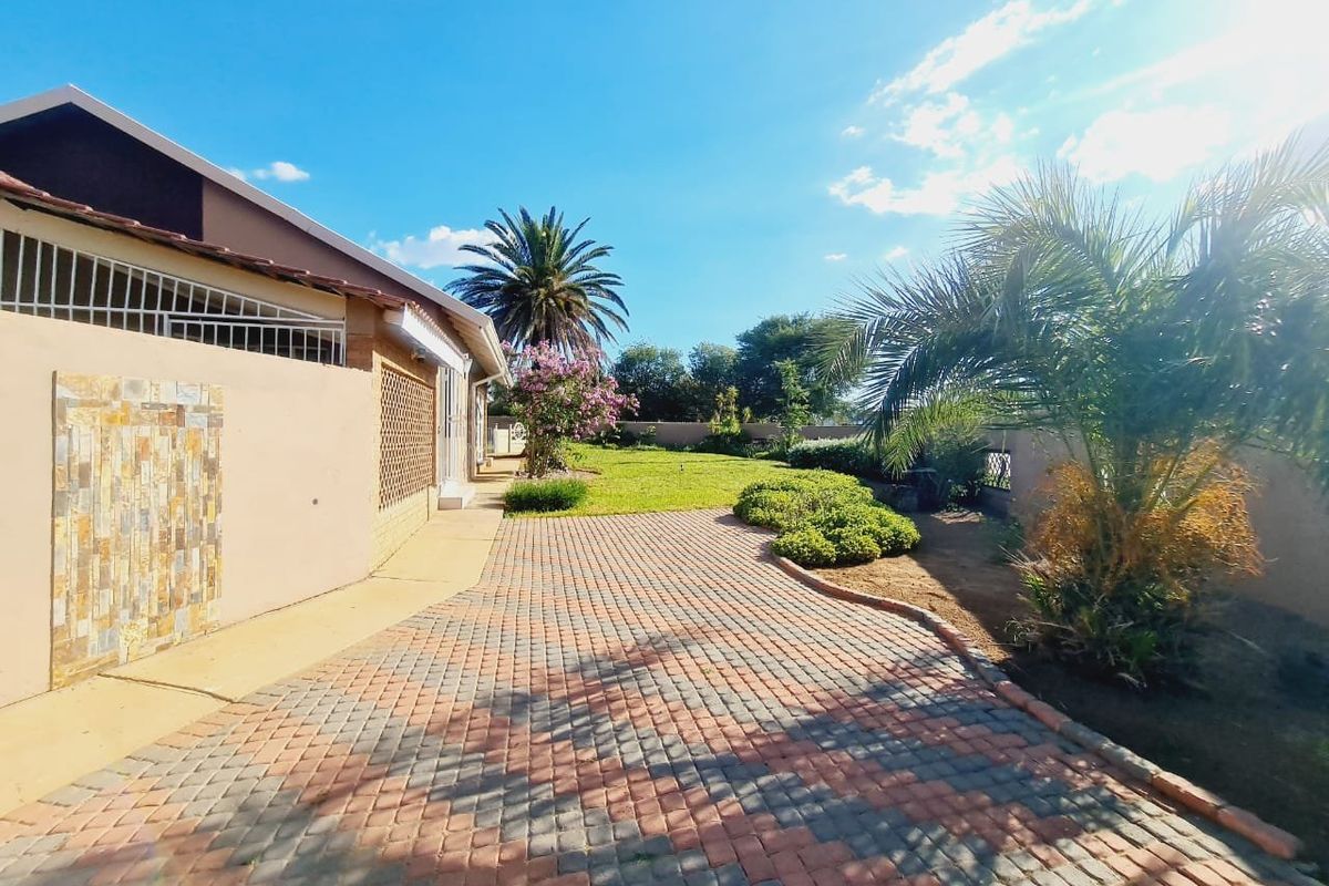 A spacious rear garden featuring a paved patio area, established landscaping, and secure boundary walls, offering a private outdoor space.